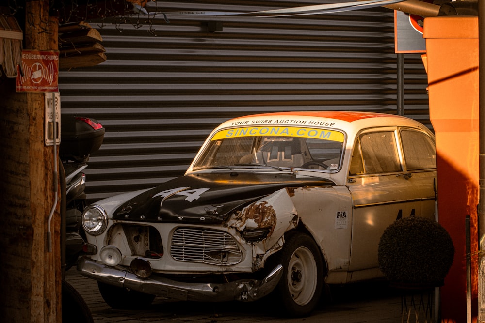 an old car that is parked in front of a garage