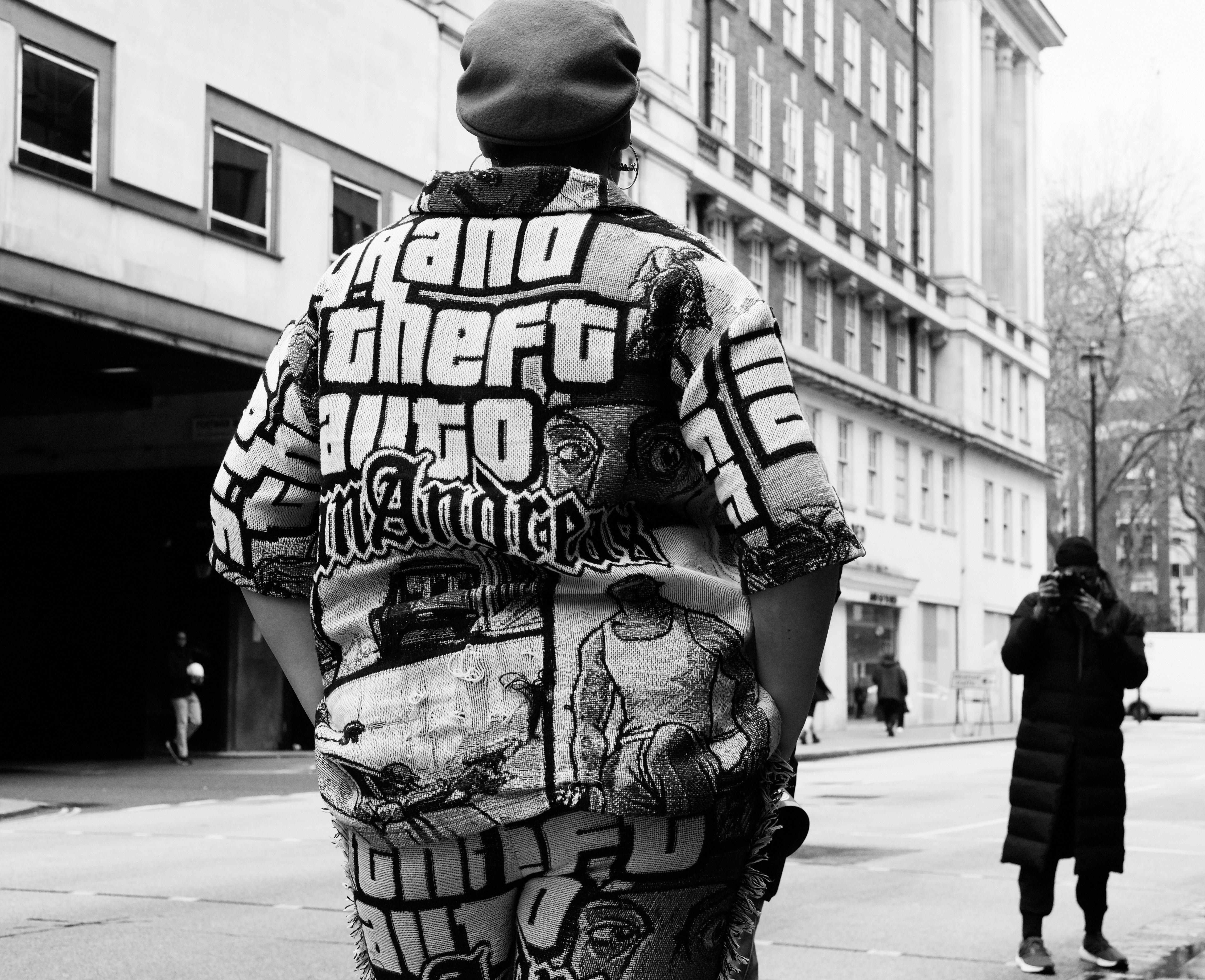 a man walking down a street next to a tall building