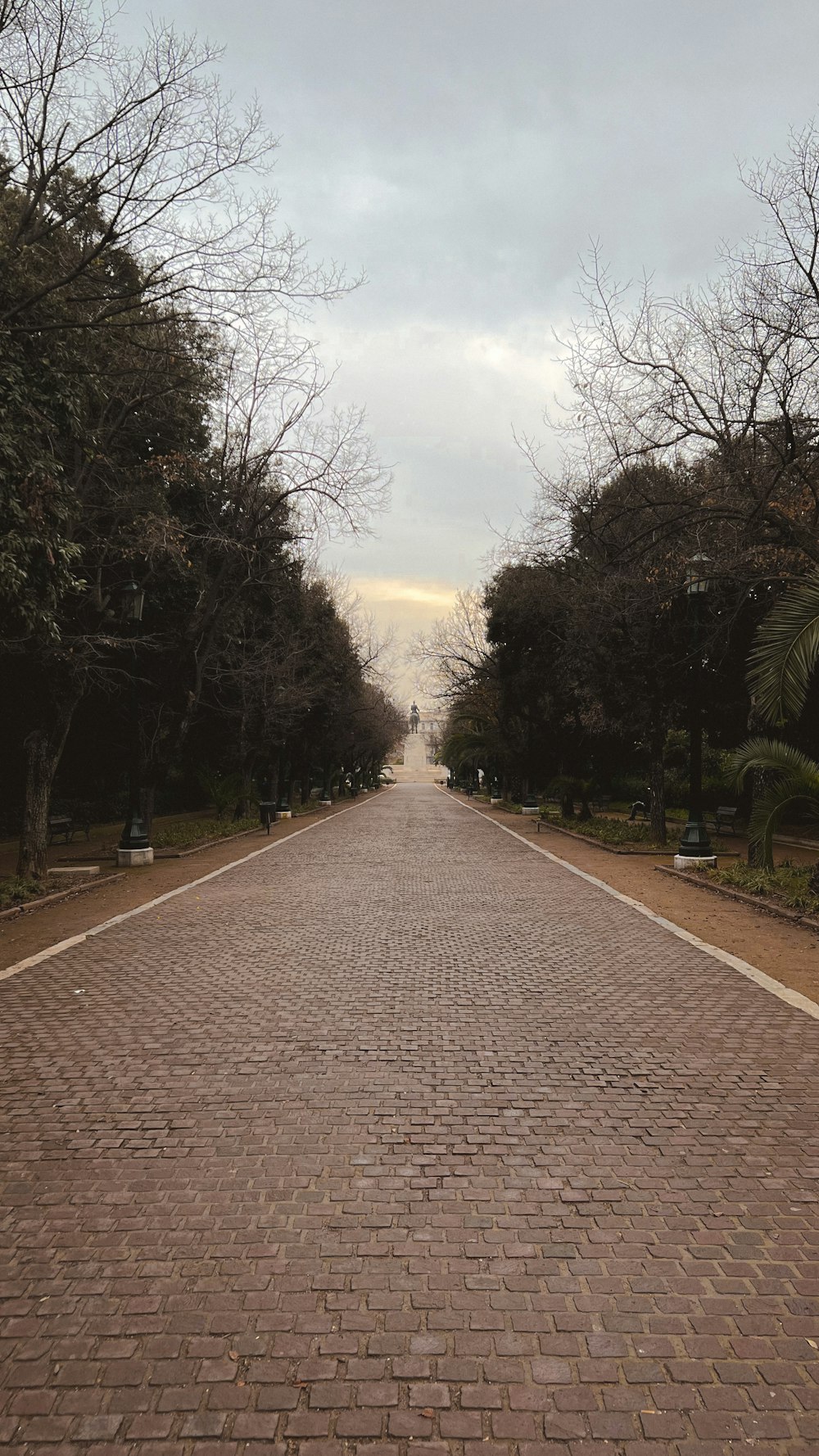 a brick road with trees lining the sides of it