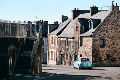 a small blue car parked in front of a stone building