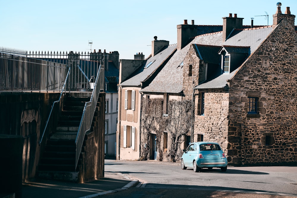 a small blue car parked in front of a stone building