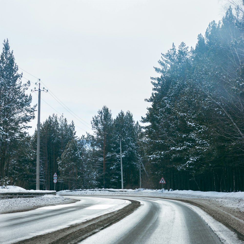 a road with snow on the ground and trees in the background