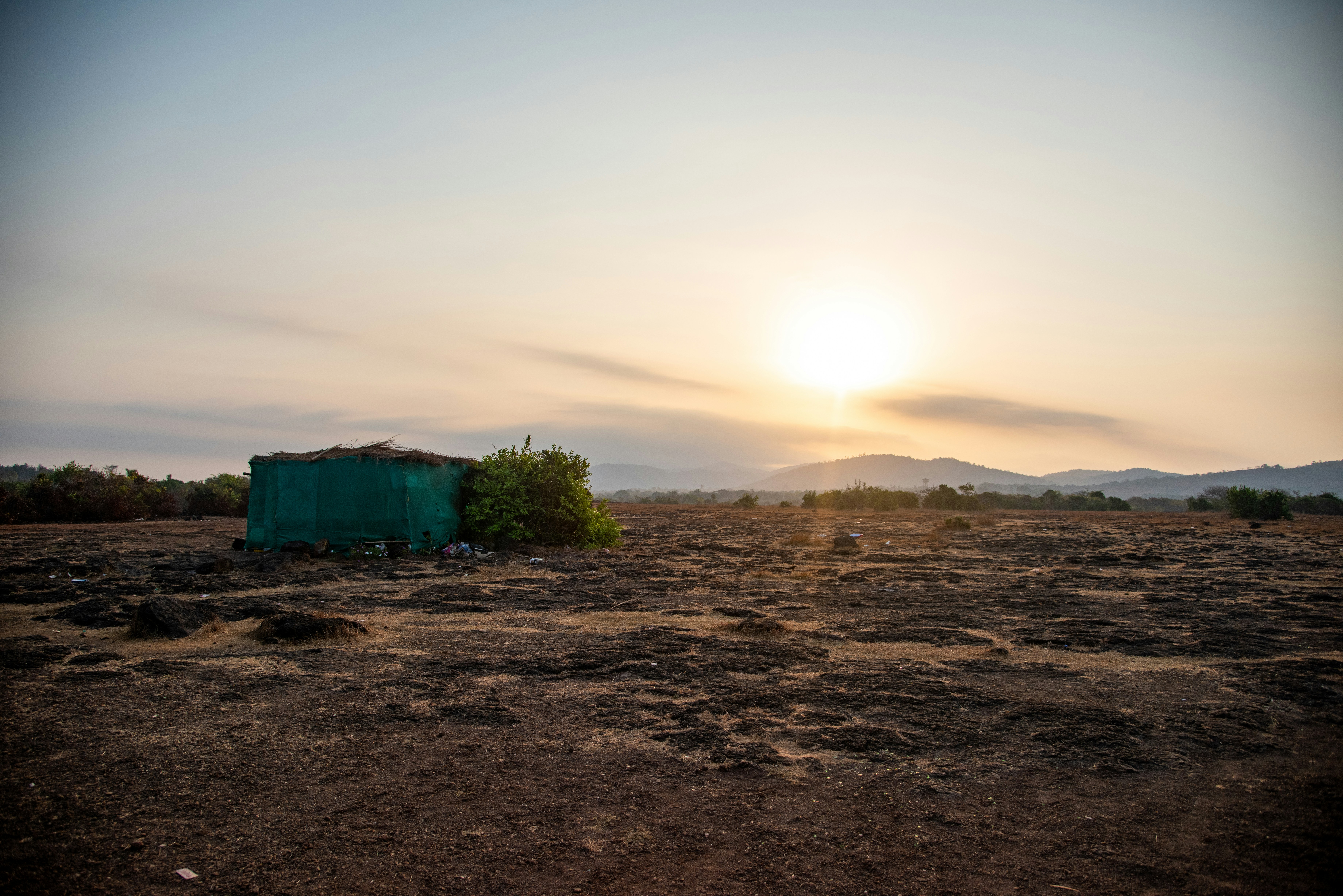 O sol está se pondo sobre um pequeno barraco no meio do deserto