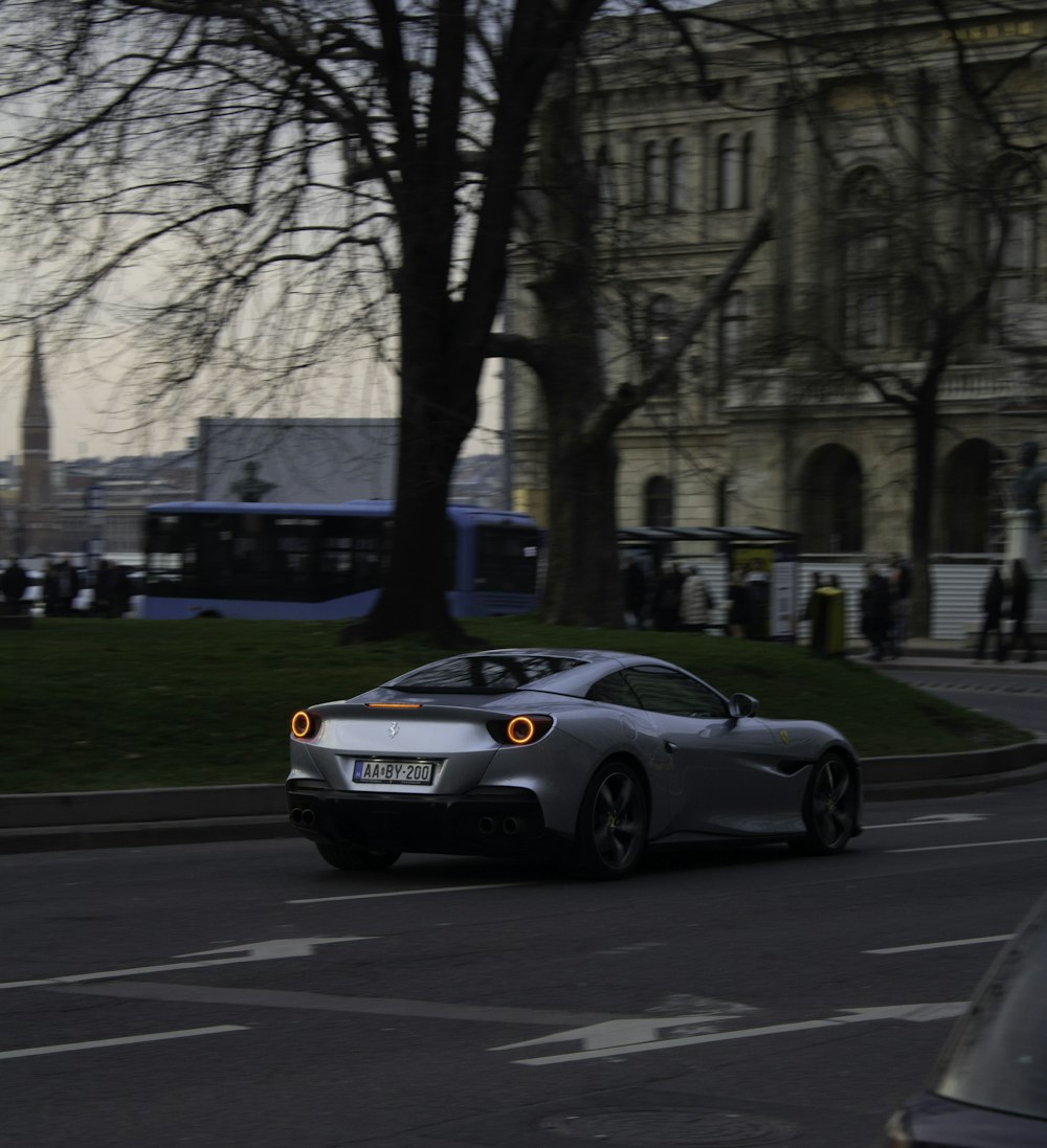 a silver sports car driving down a city street