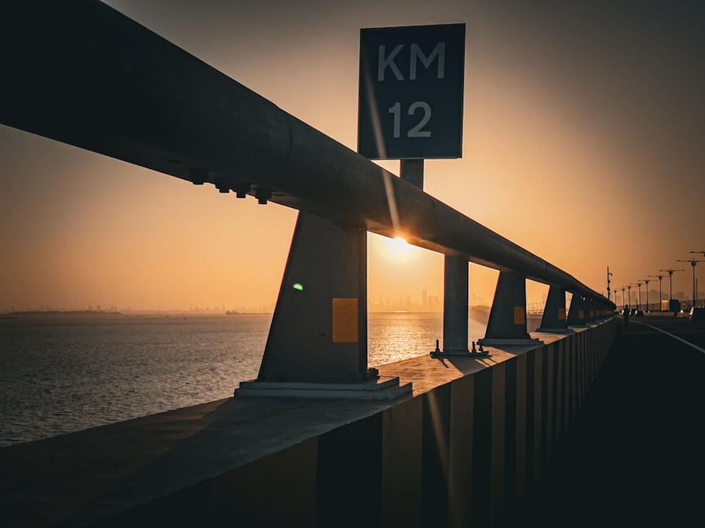 the sun is setting over the ocean and a bridge