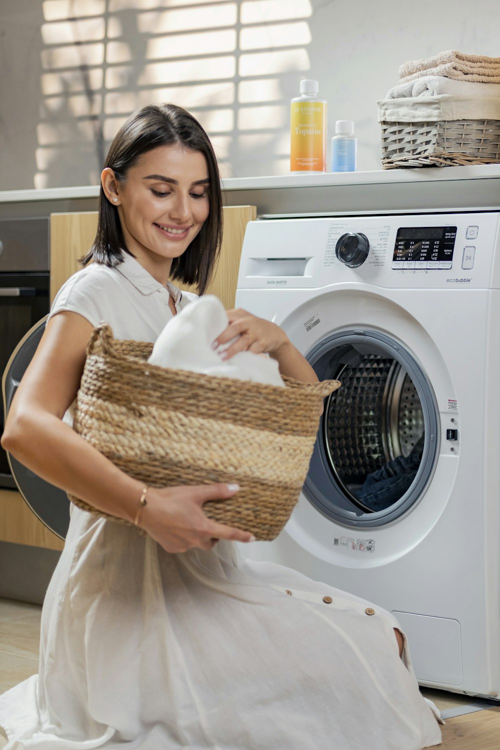 a woman is holding a basket near a washing machine