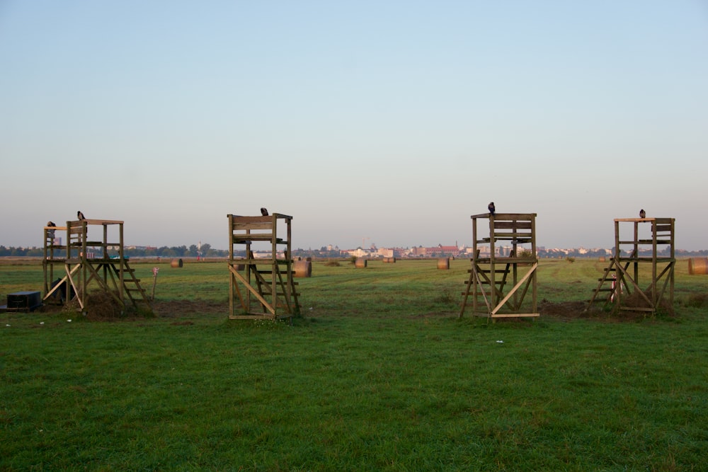 a group of wooden chairs sitting on top of a lush green field