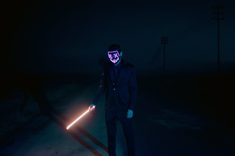 a man wearing a mask and holding a light saber