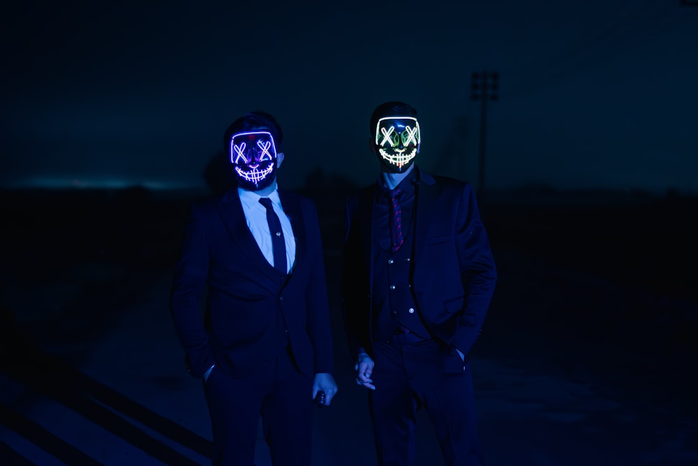 two people wearing masks standing in the dark