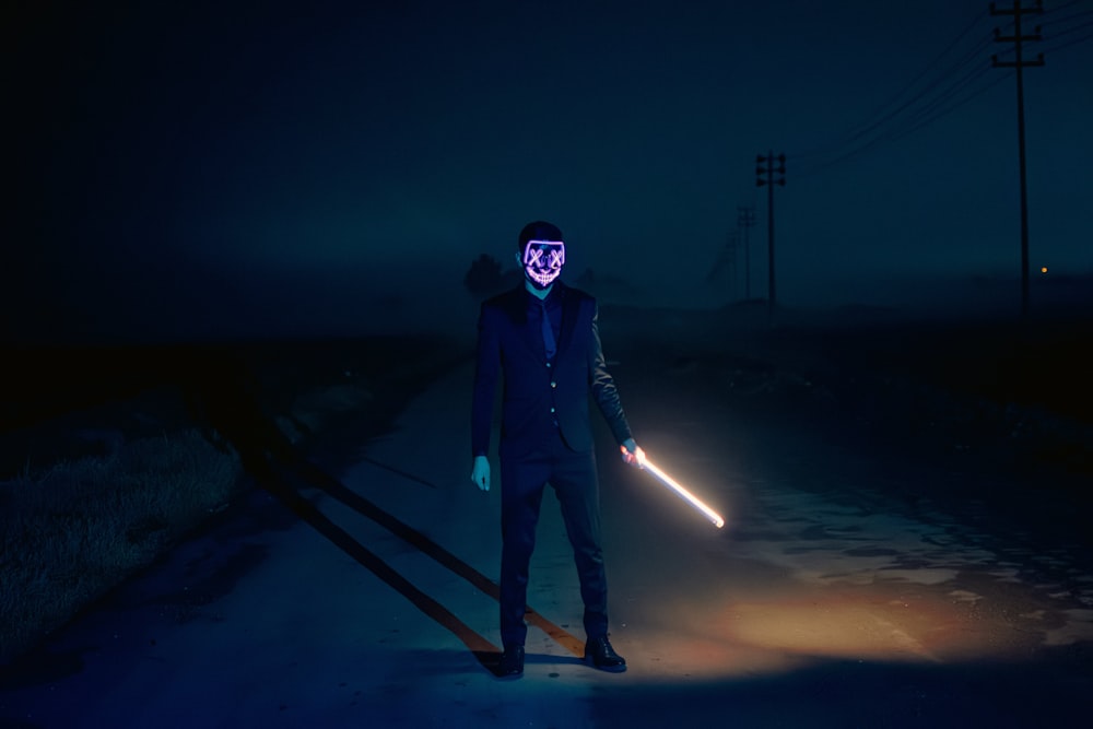 a man wearing a mask and holding a light saber