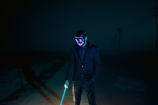 a man wearing a neon mask and holding a cane