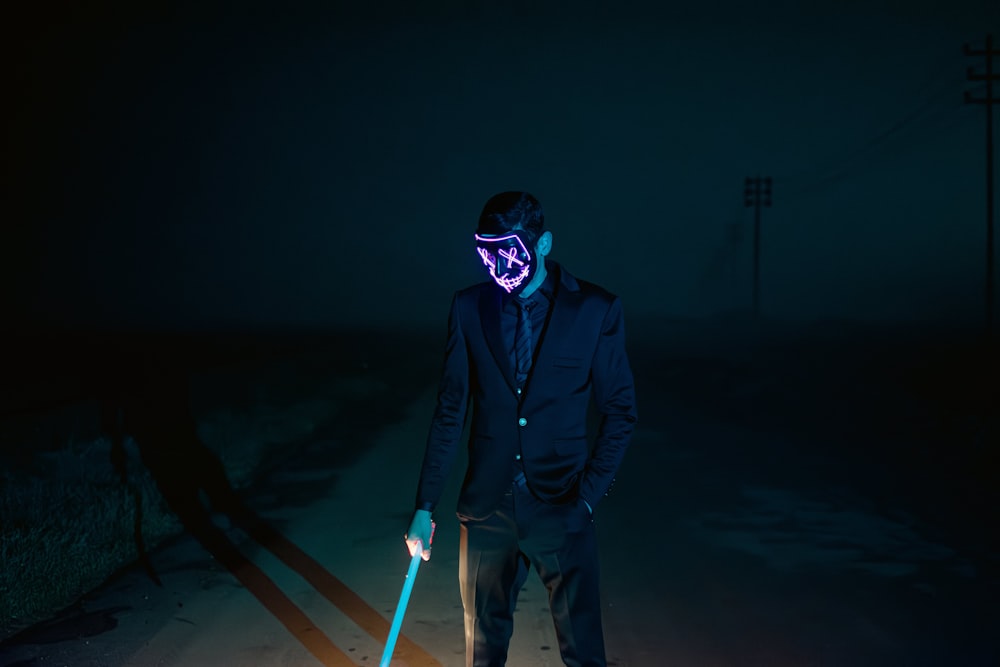 un uomo che indossa una maschera al neon e tiene in mano un bastone