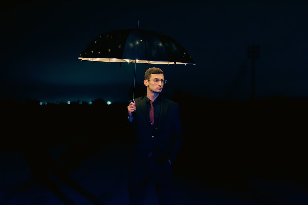 ein Mann mit einem Regenschirm im Dunkeln