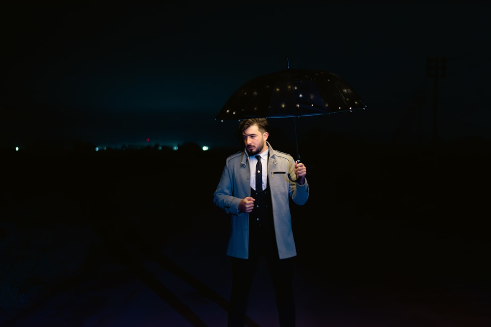 a man standing in the dark holding an umbrella