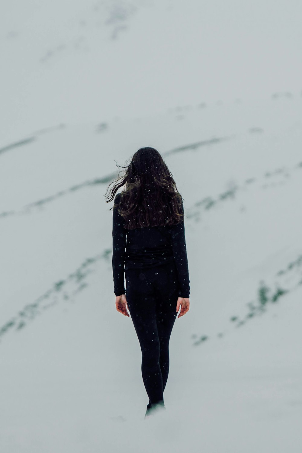 a woman walking in the snow with her back to the camera