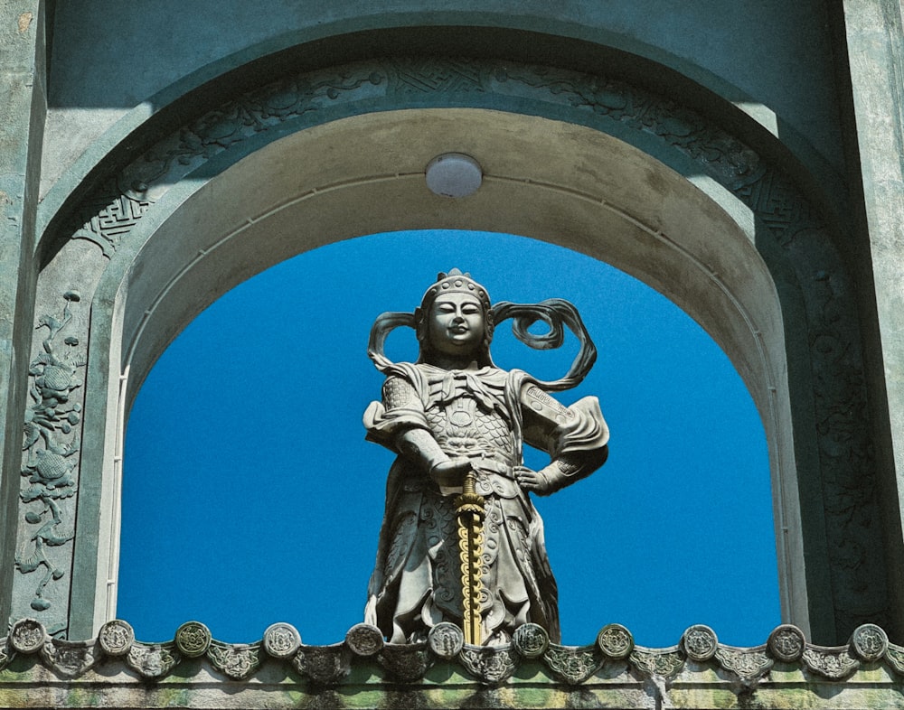 une statue d’une personne tenant un serpent au sommet d’un bâtiment