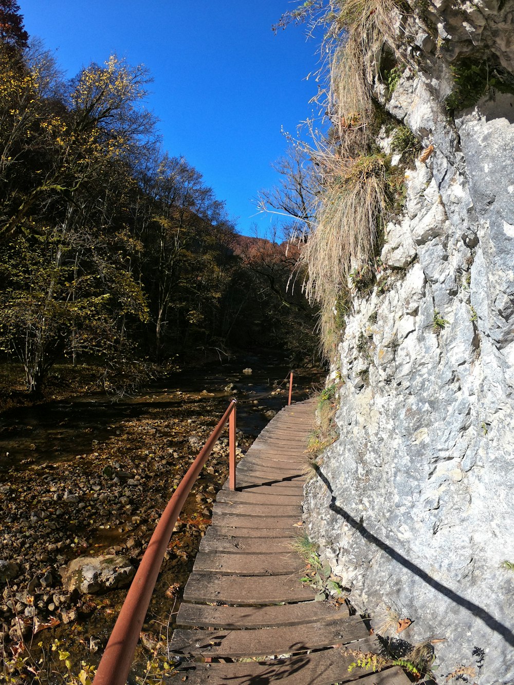 a stone wall with a metal railing next to a river