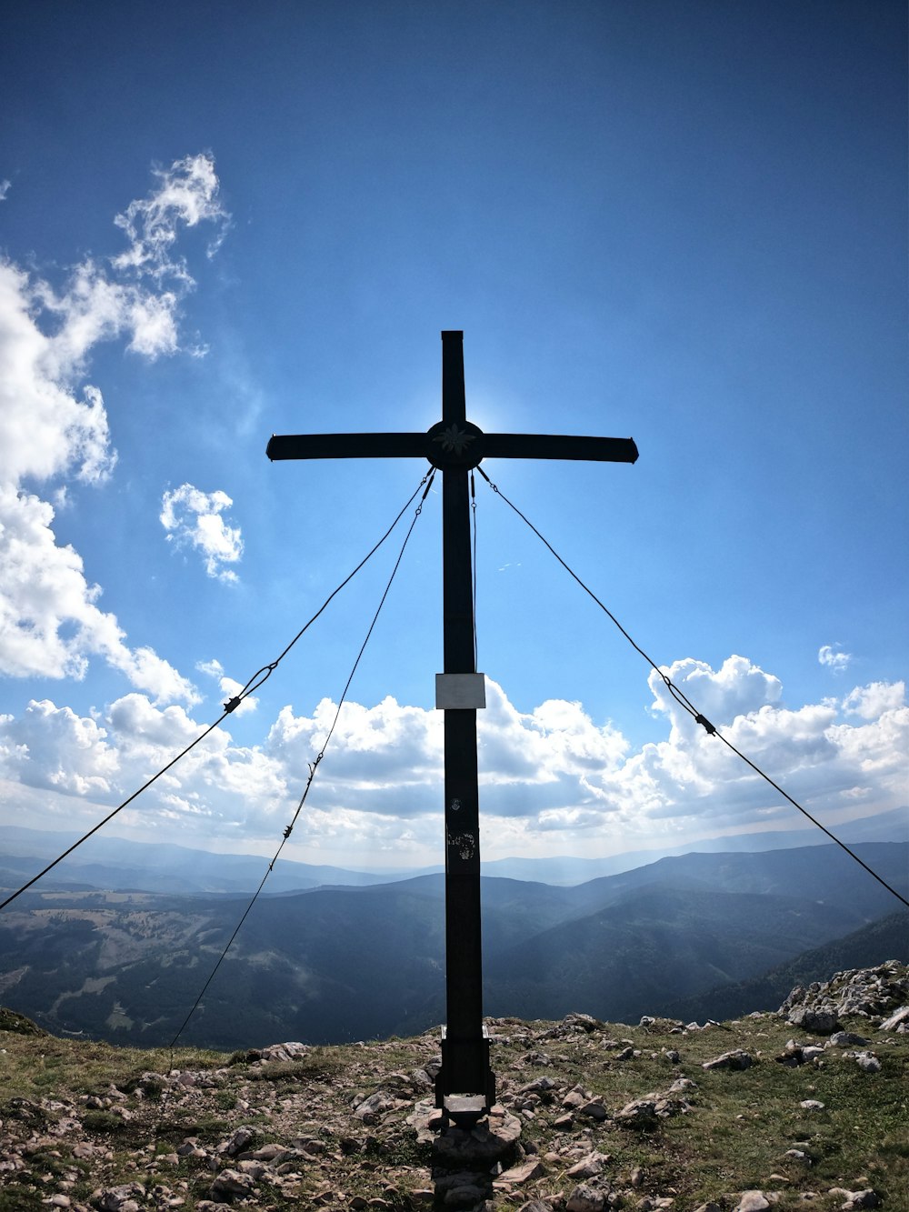 a cross on top of a hill with mountains in the background