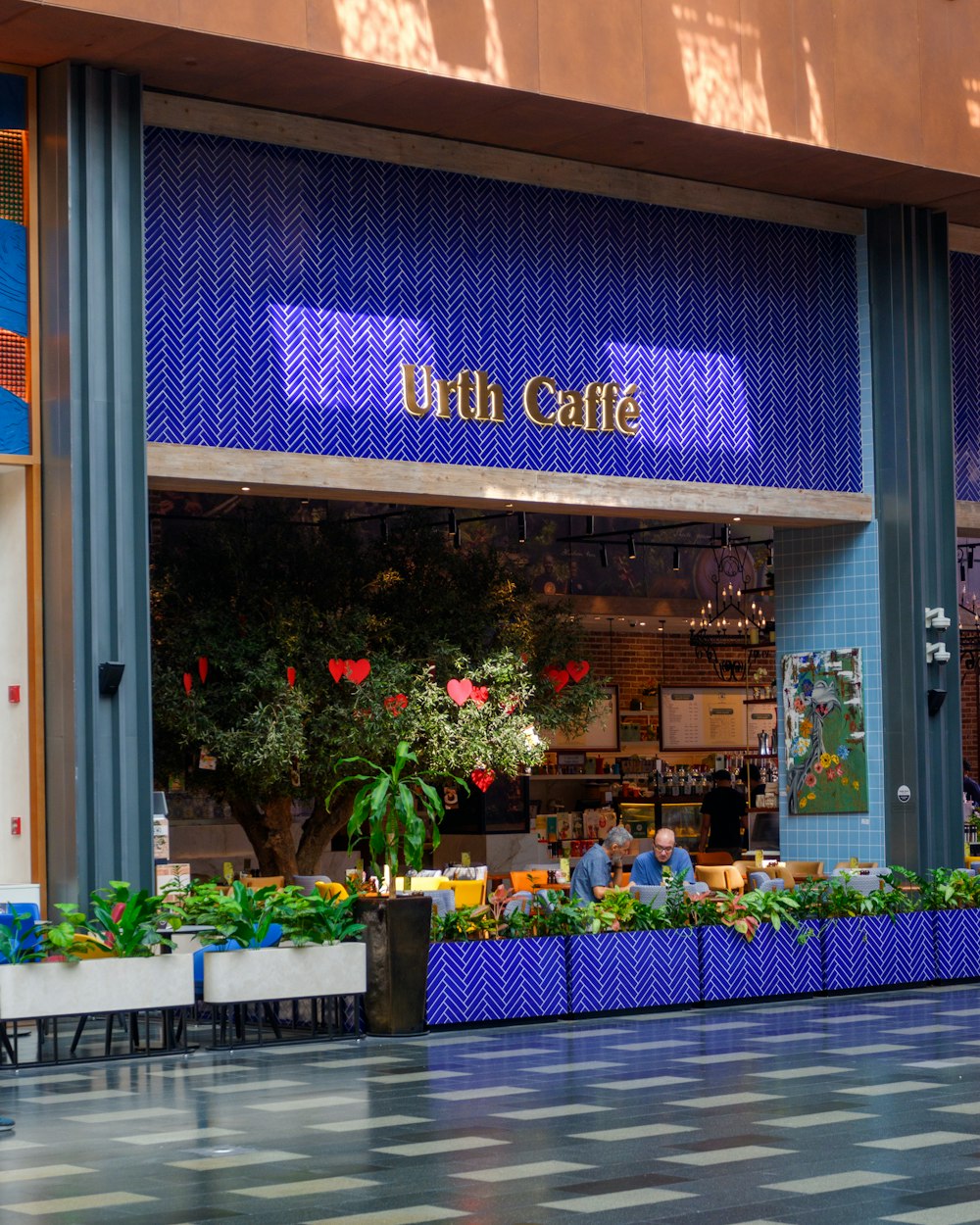a store front with plants and potted plants outside
