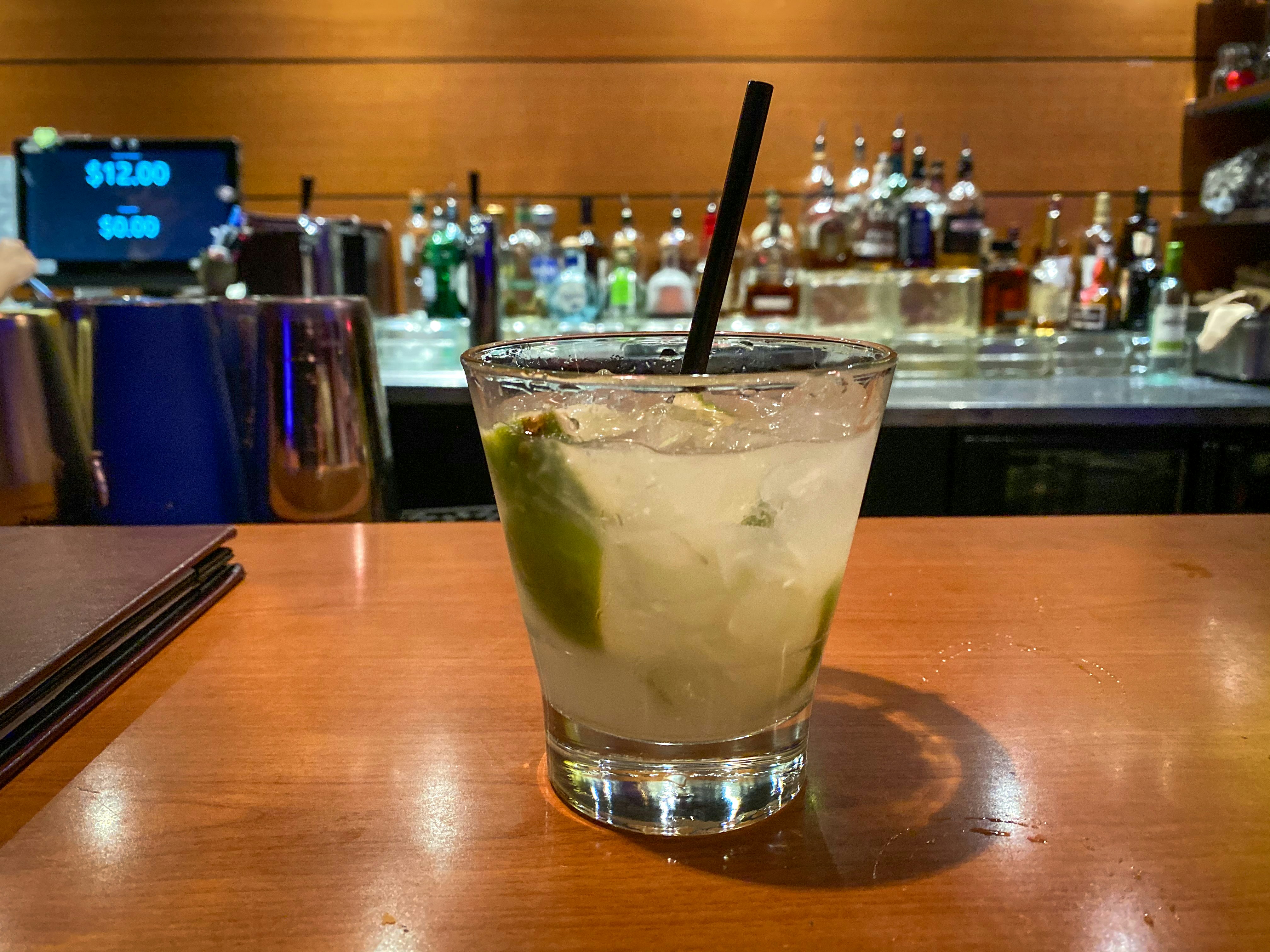 Colorful cocktails and cold beer bottles on a bar counter with ice and lime, bright and airy bar setting