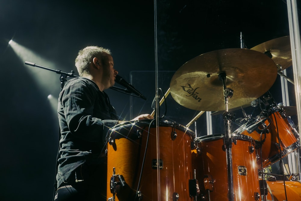 um homem tocando bateria na frente de um microfone