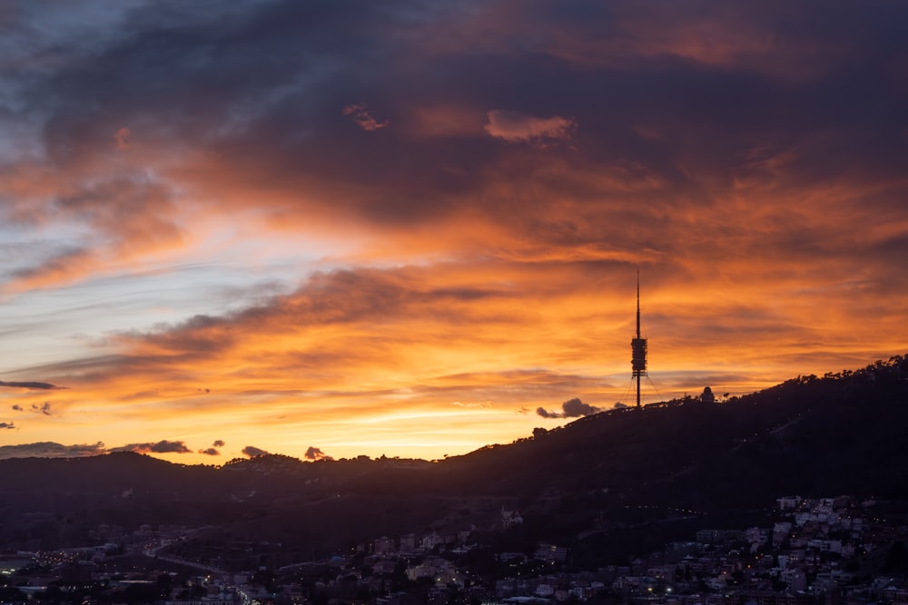 a sunset view of a city with a tower in the distance