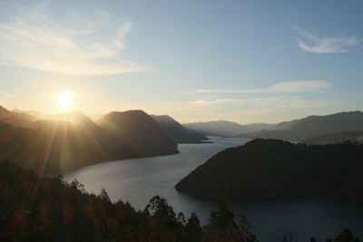 the sun is setting over a mountain lake