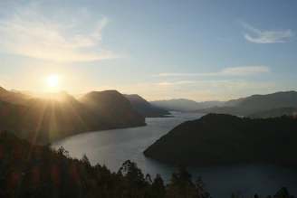 the sun is setting over a mountain lake