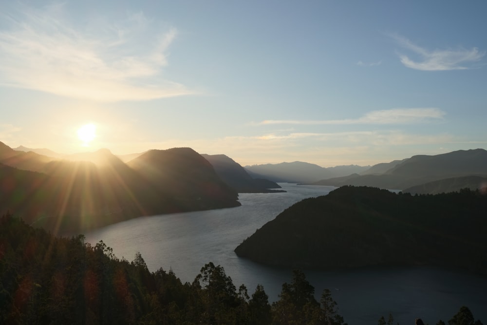 the sun is setting over a mountain lake