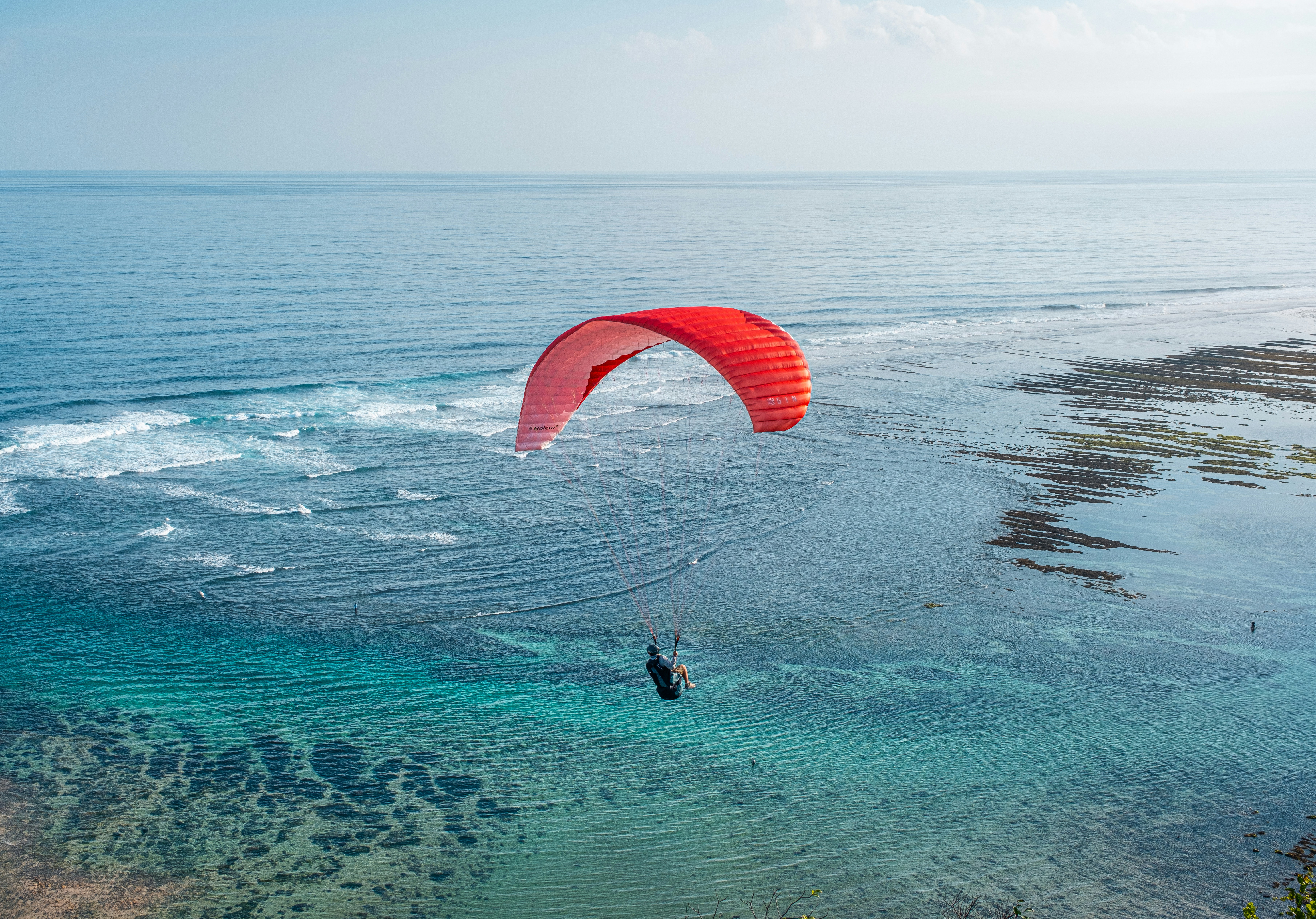 晴れた日に海でパラセーリングをする人