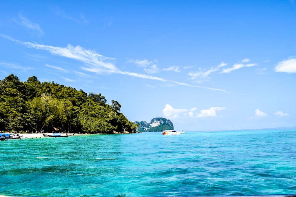 a beach with boats in the water and a small island in the distance