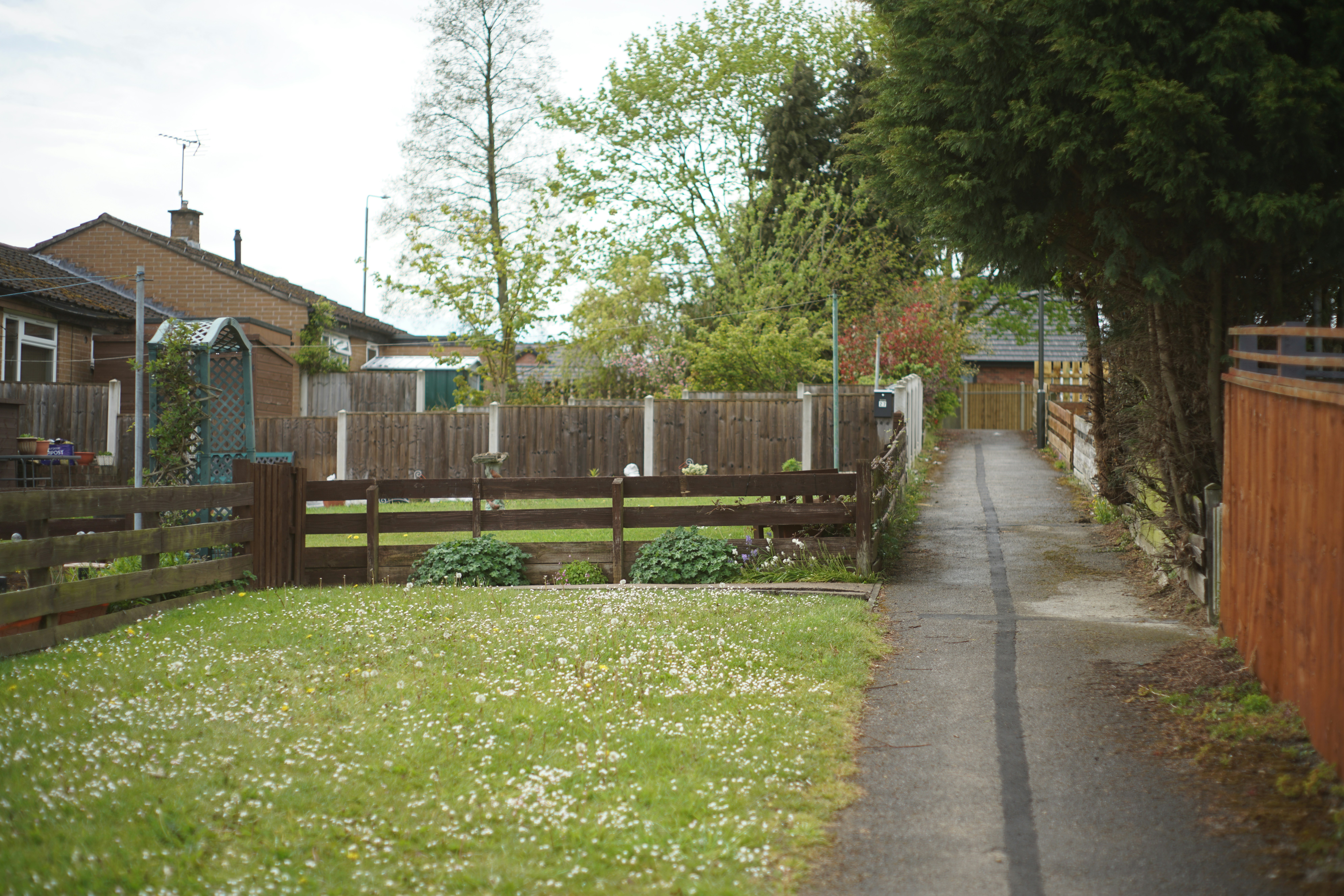 a narrow road with a fence and a house in the background