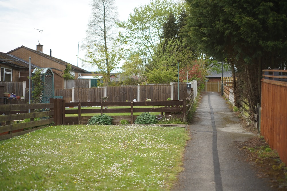 a narrow road with a fence and a house in the background