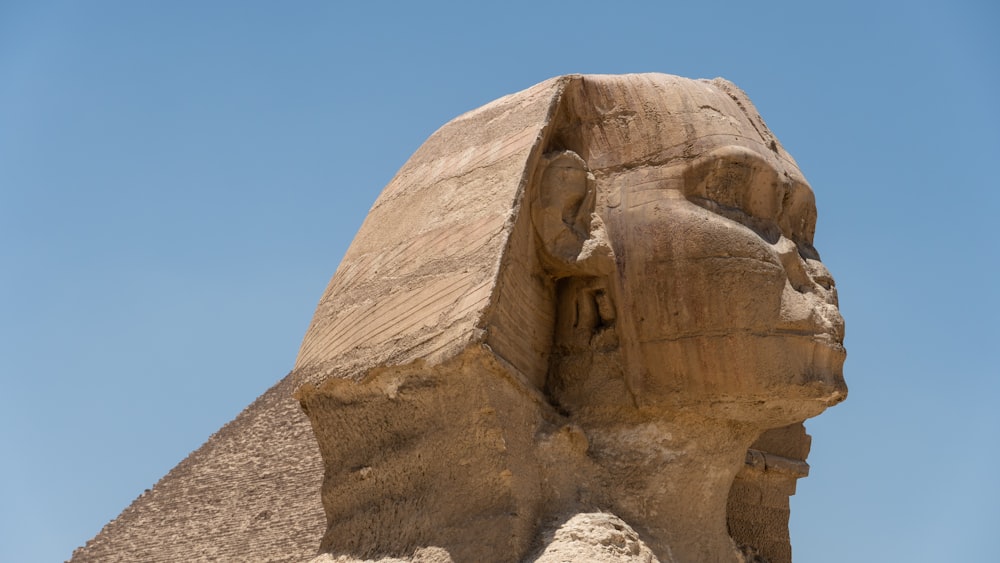 une grande statue d’un sphinx devant un ciel bleu
