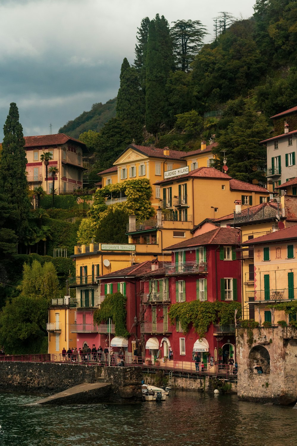 a row of houses on a hillside next to a body of water