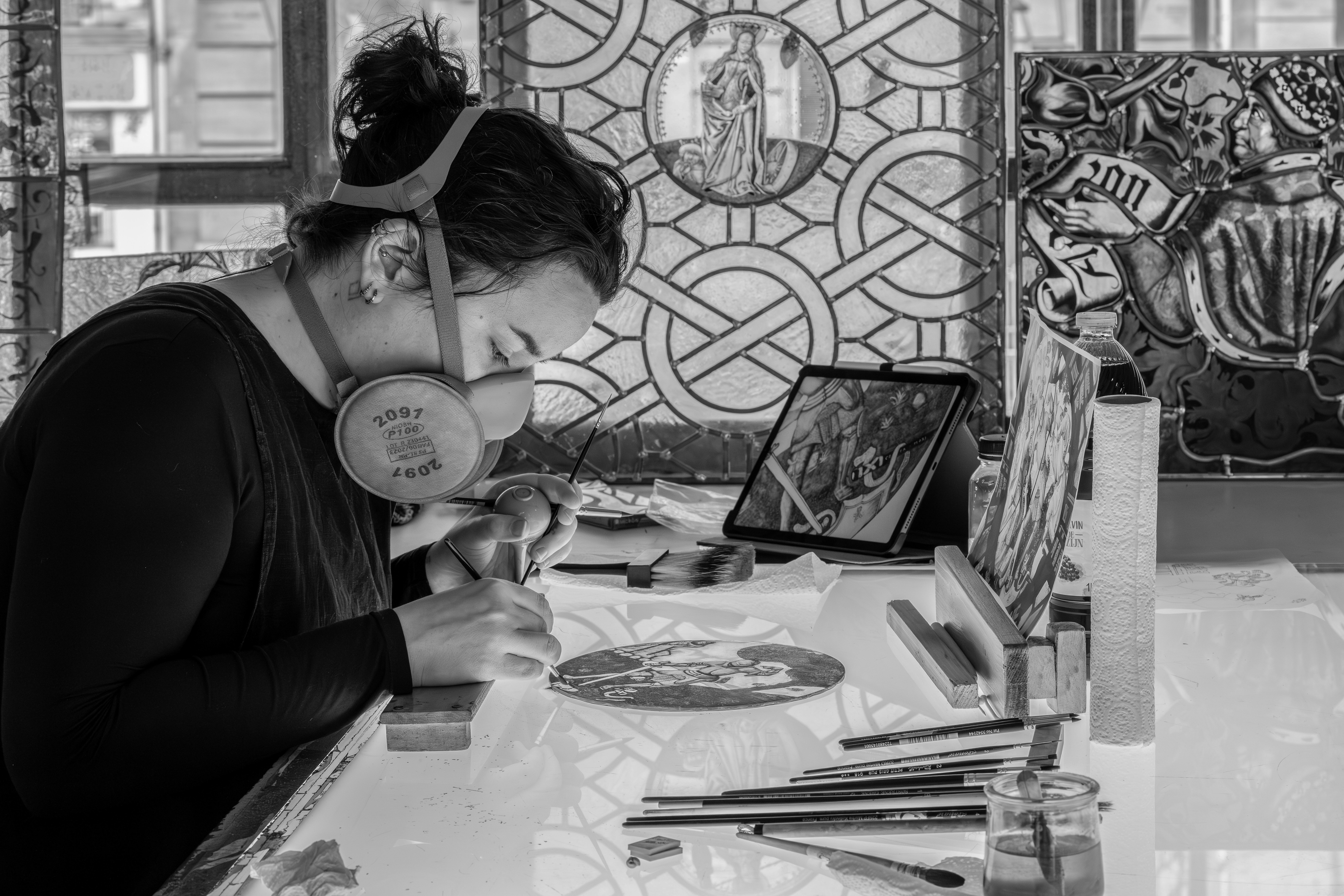 a woman sitting at a table working on a piece of art