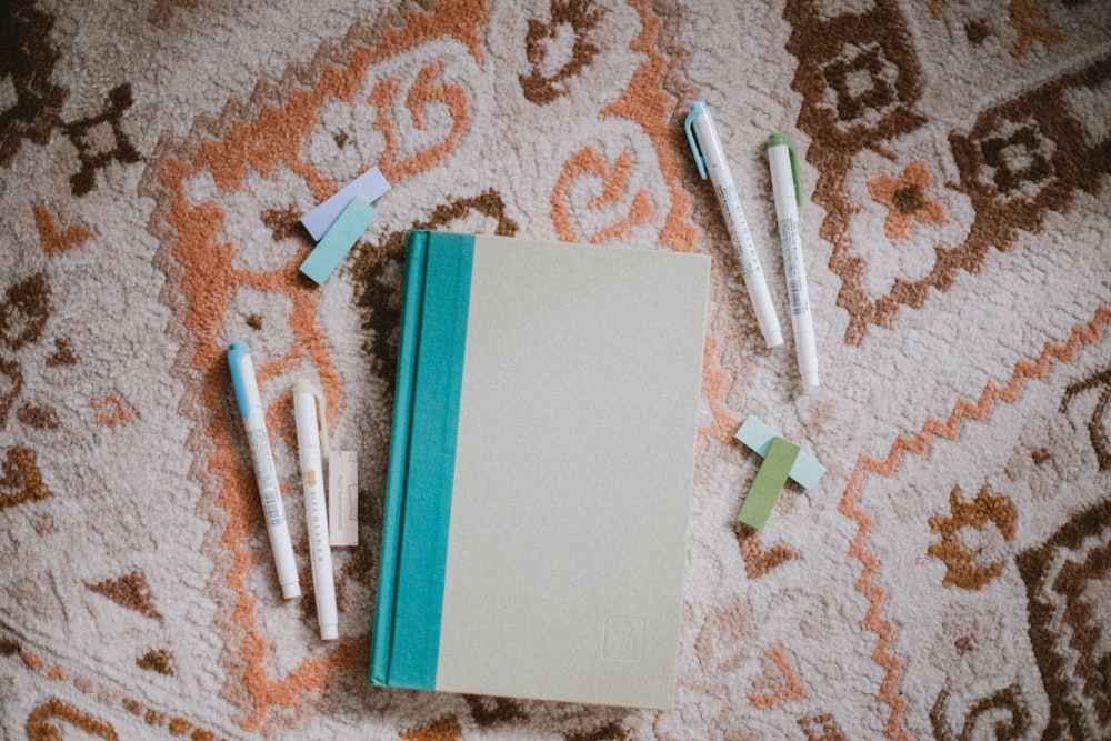 a notebook and three toothbrushes laying on a carpet