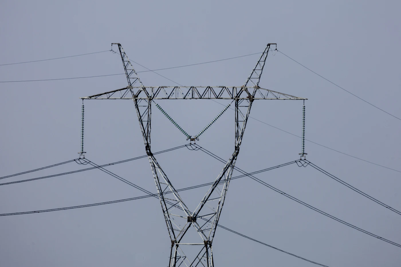 Overhead high-voltage power line against a grey sky