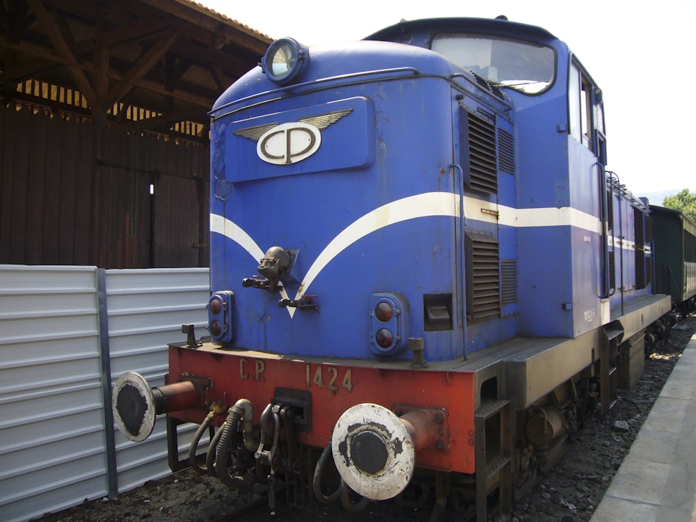 a blue and white train parked next to a train station