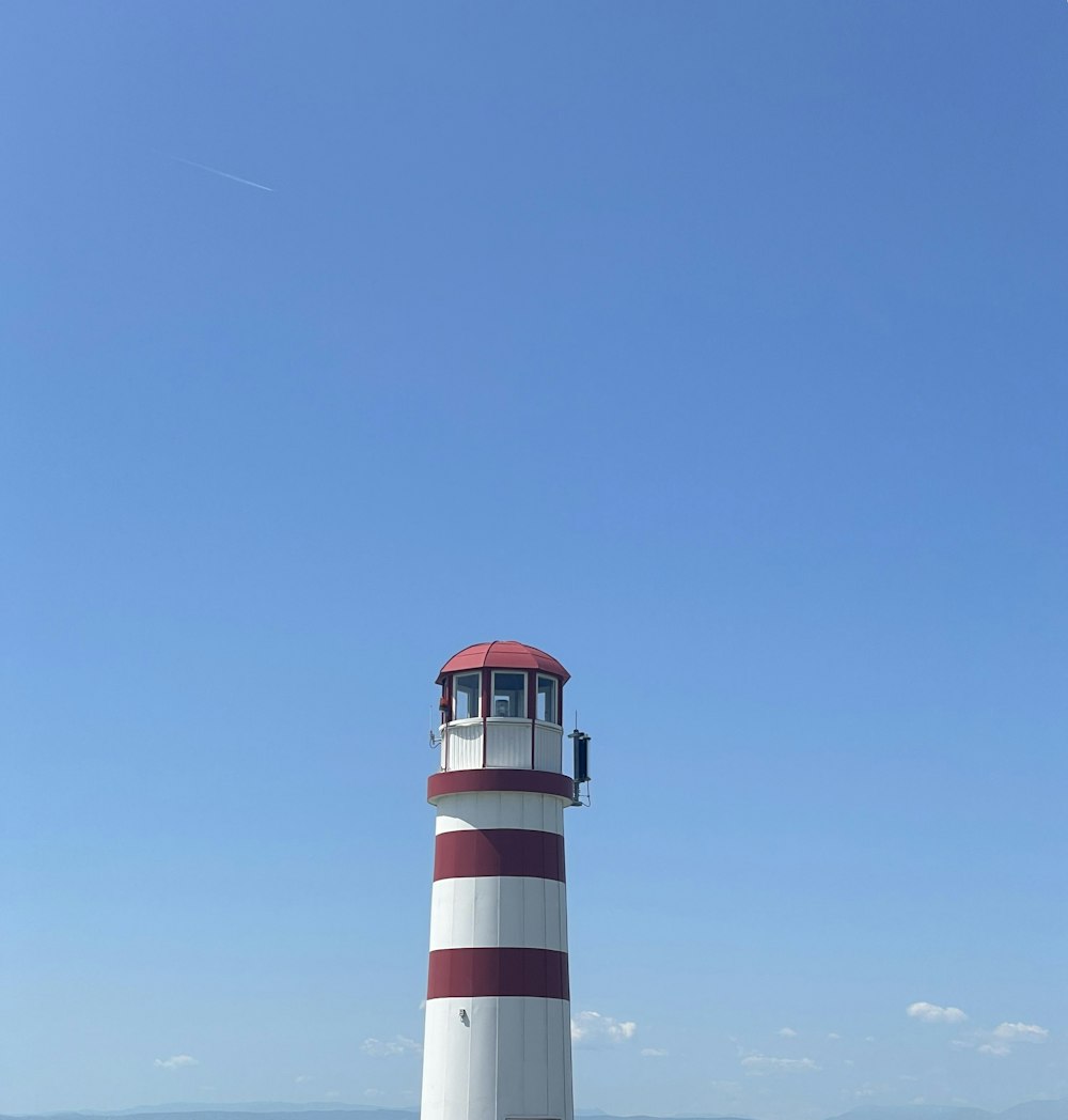 a red and white lighthouse sitting on top of a sandy beach