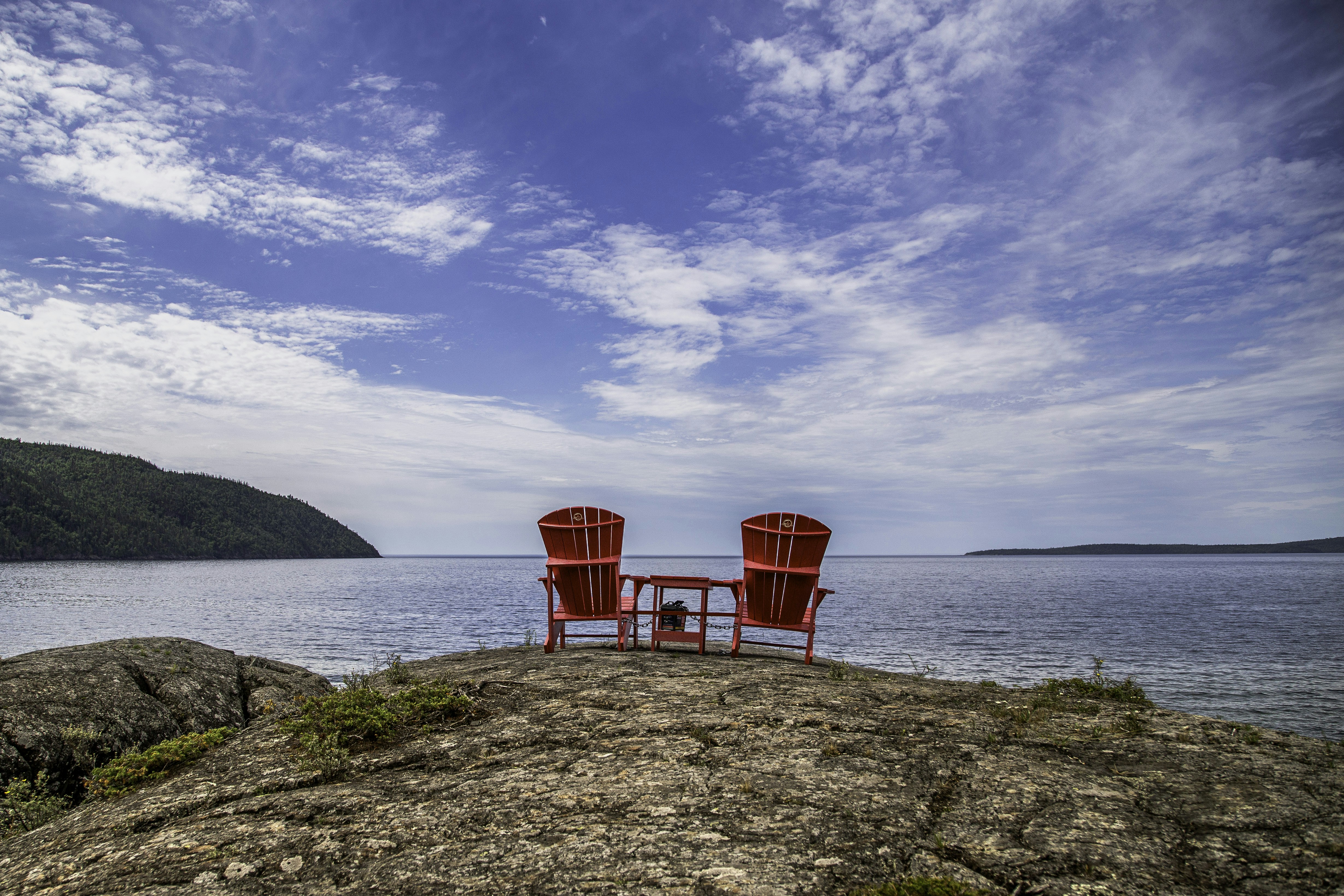 a couple of red chairs sitting on top of a rock