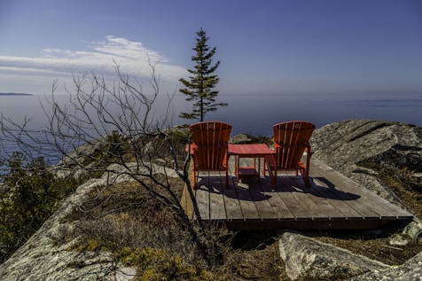 two red chairs sitting on top of a wooden platform