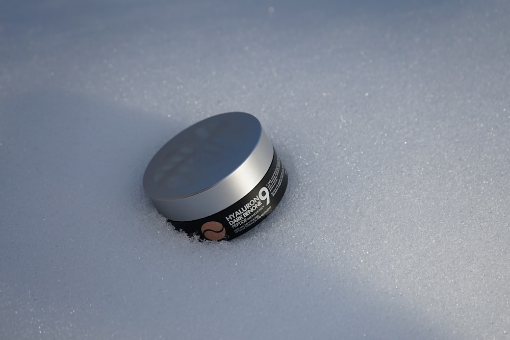 a jar of cream sitting on top of a snow covered ground