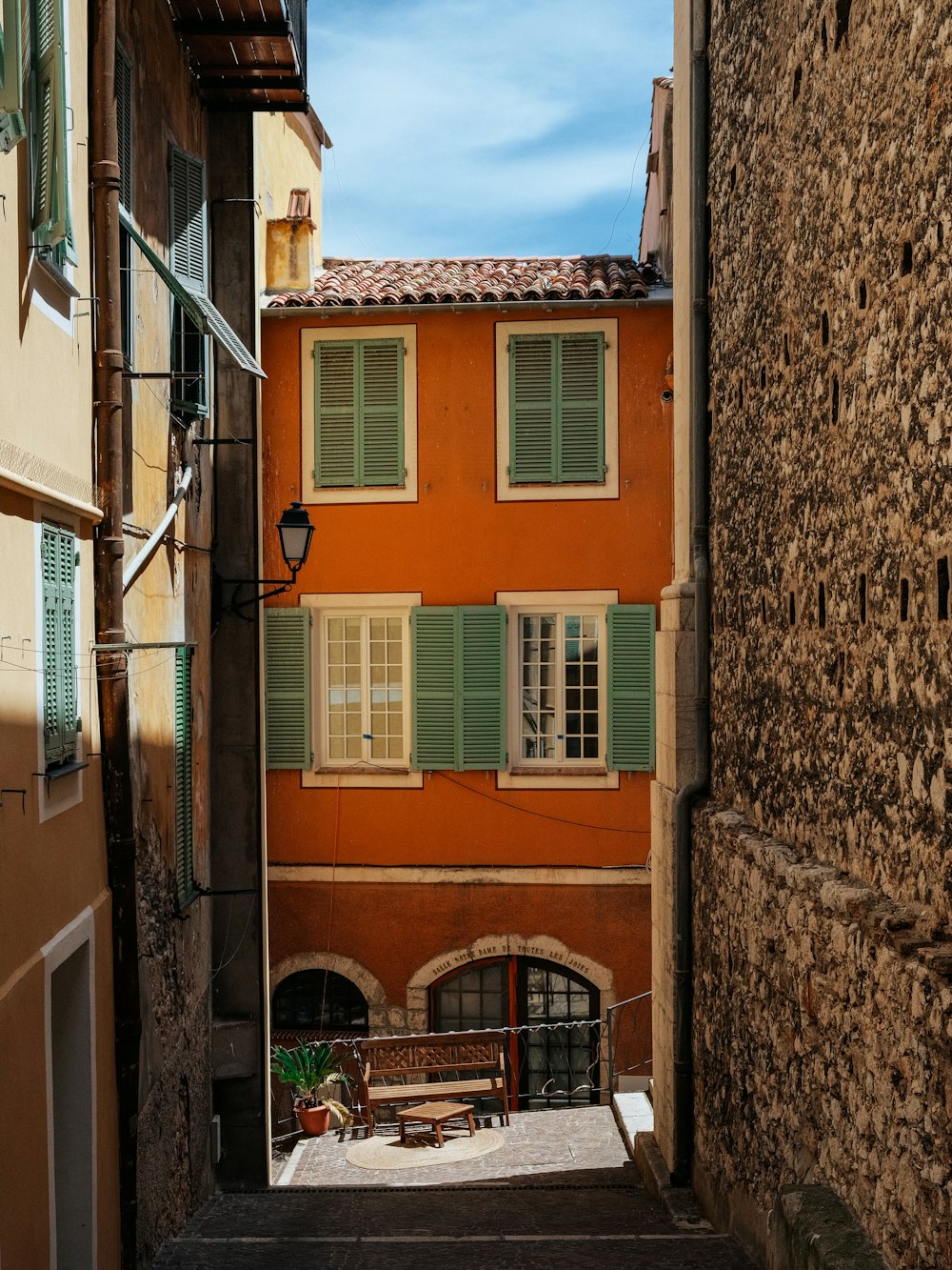 a narrow alley way with a bench between two buildings
