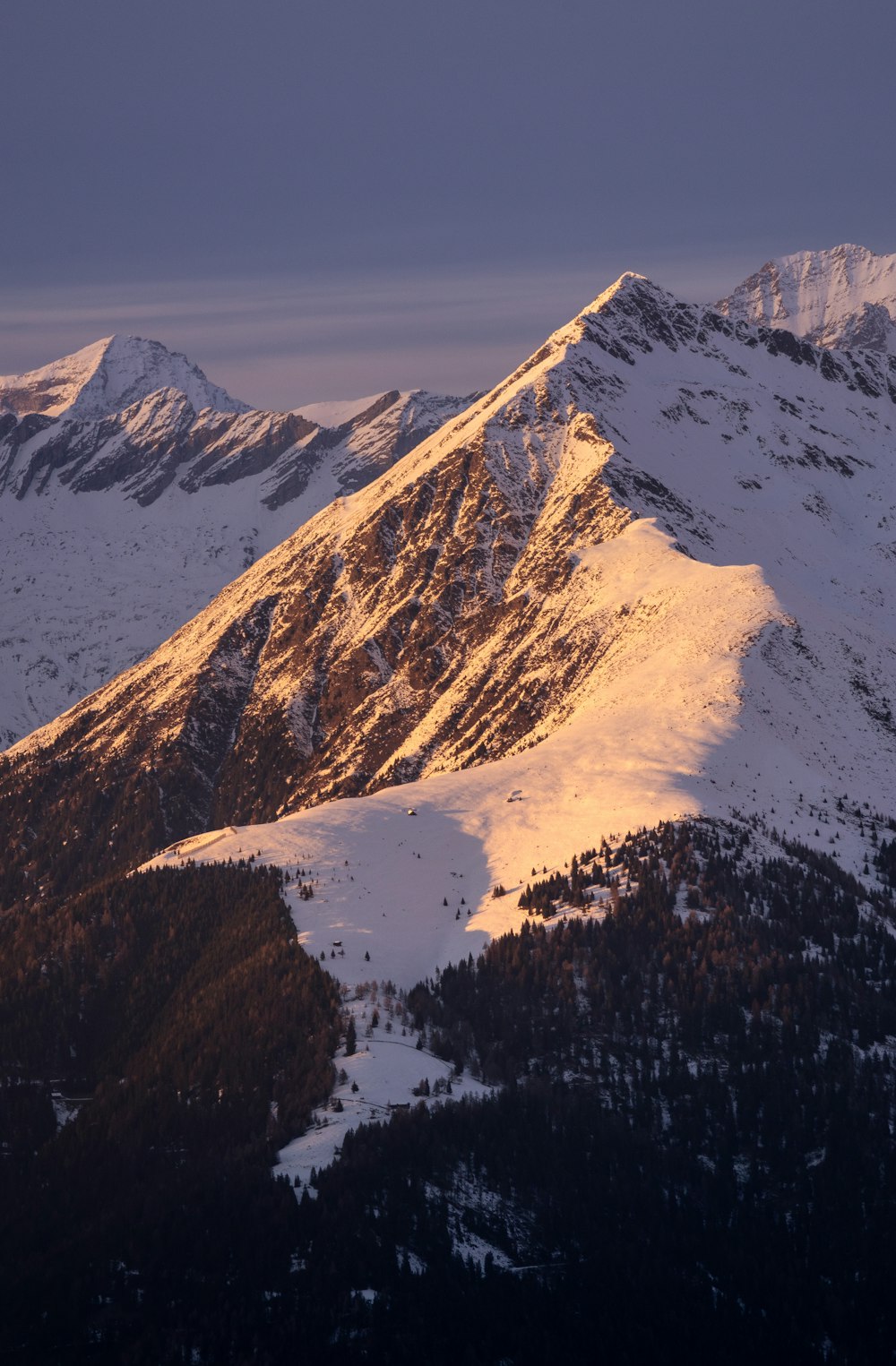 a view of a snowy mountain range at sunset