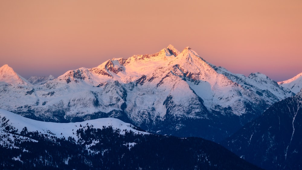 a snow covered mountain with a pink sky in the background