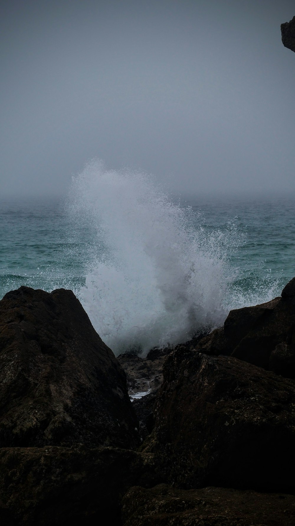 a large wave crashing into a rocky shore