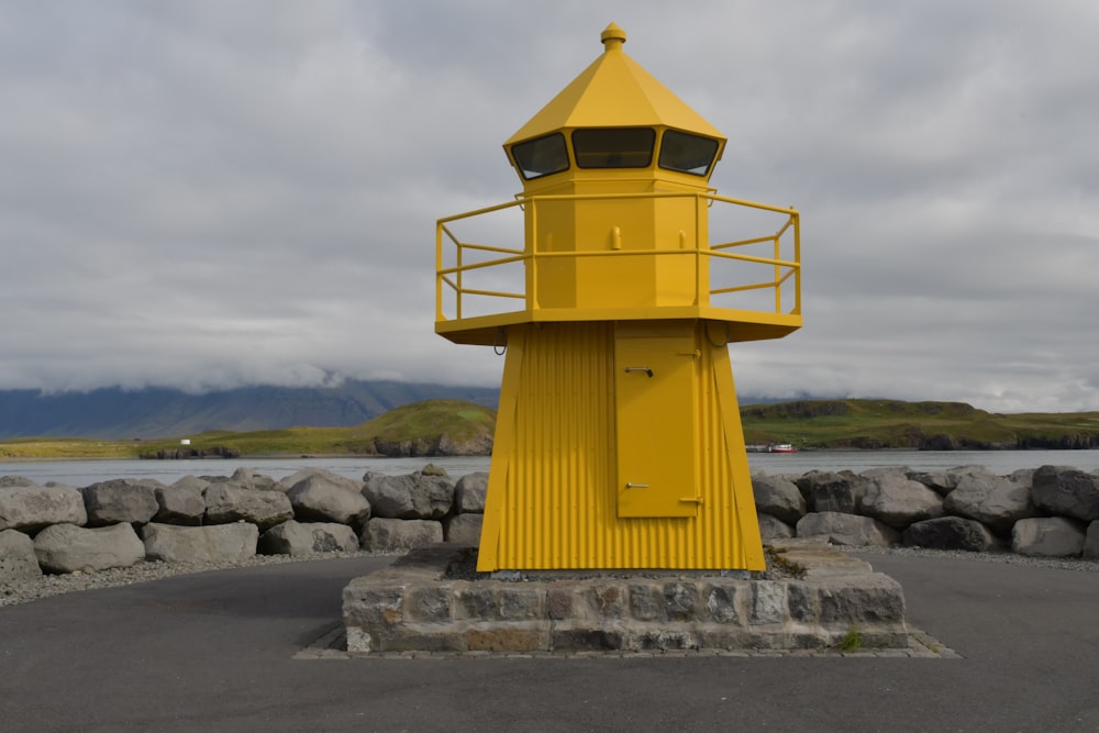 a yellow lighthouse sitting on top of a stone wall