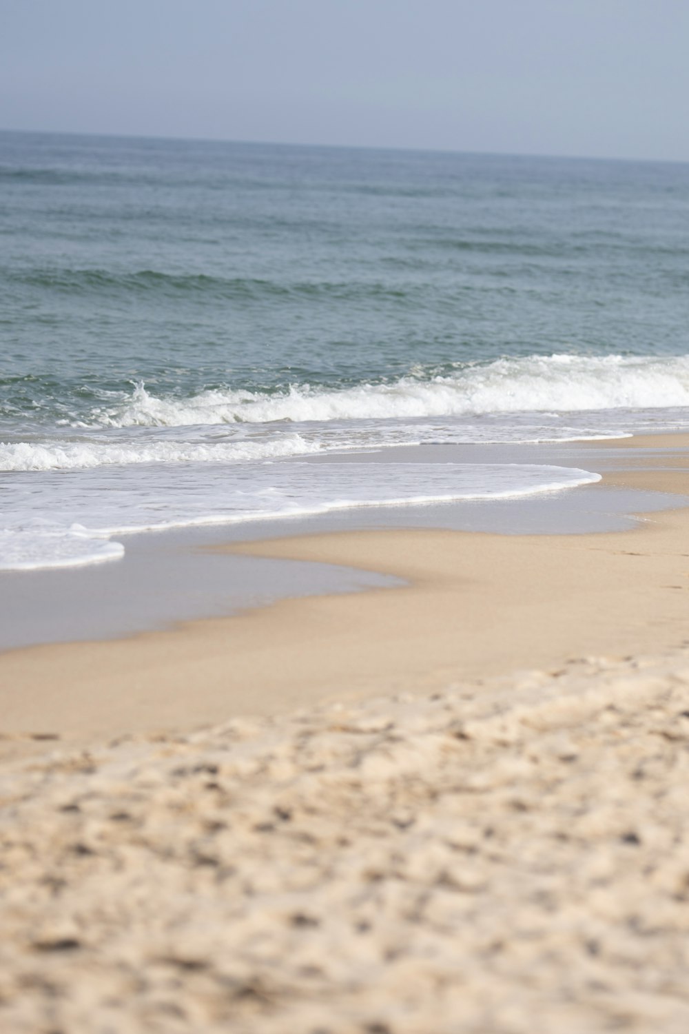 a person walking on a beach carrying a surfboard