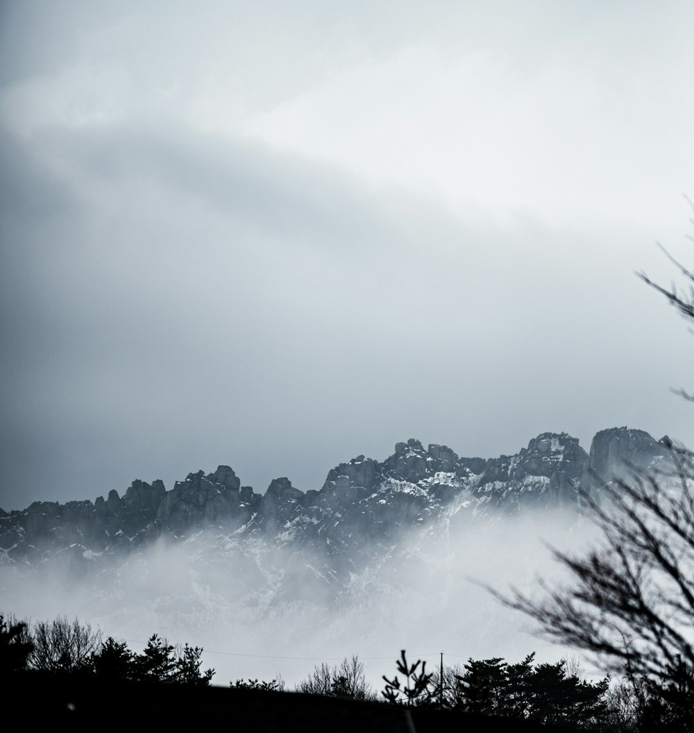 a black and white photo of a mountain covered in fog